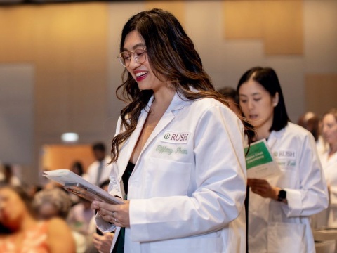 Students standing and reciting at a white coat ceremony