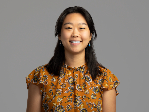 Emily Xu, admissions specialist, wearing a mustard yellow, paisley blouse. 