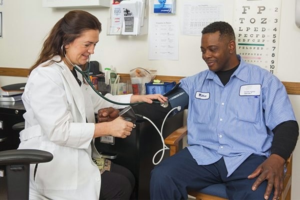 A nurse wearing a white coat takes a patient's blood pressure