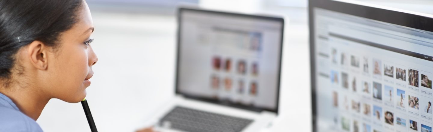 A seated person looking at two computer monitors