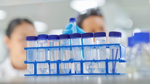 A rack of laboratory samples, with researchers out of focus behind