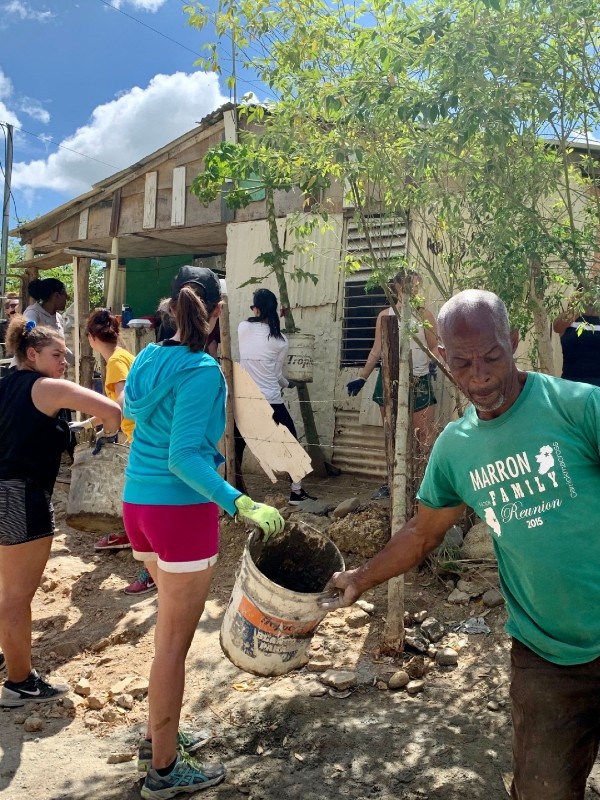 A group of people passing buckets to one another outside a house