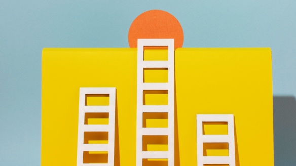 3 ladders of various heights approaching the top of a yellow box.