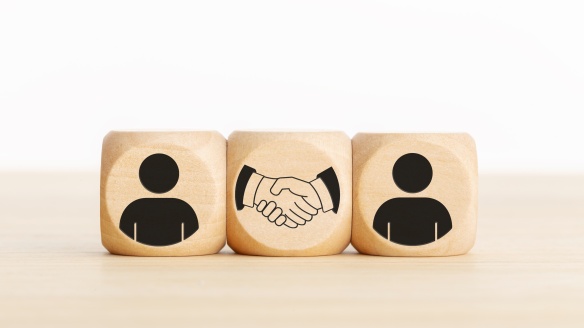 3 wooden blocks in line with people outlines and handshake on them