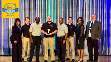 A group of students and faculty standing together on stage holding an award